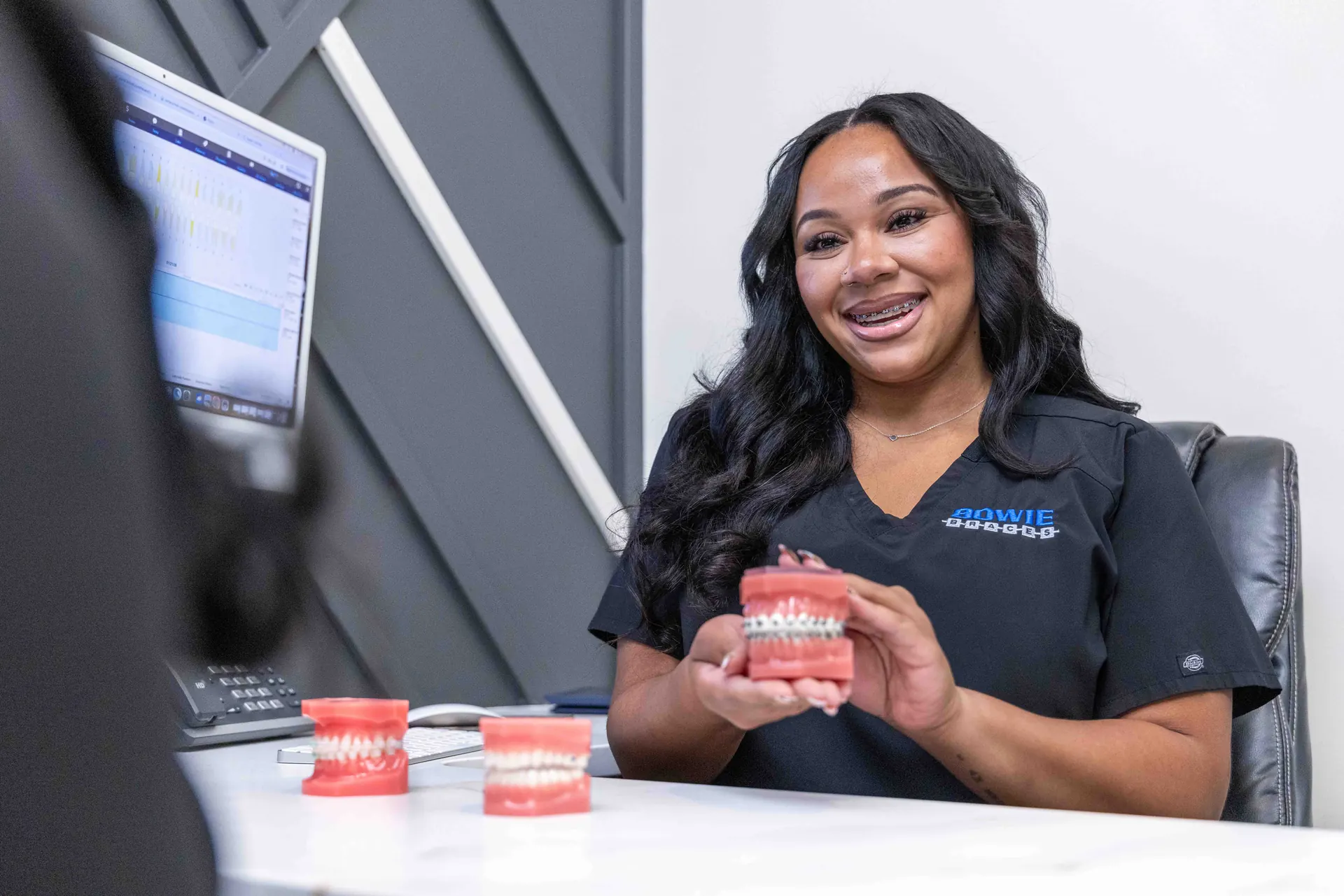 A Bowie Braces team member holding braces and aligner treatment models